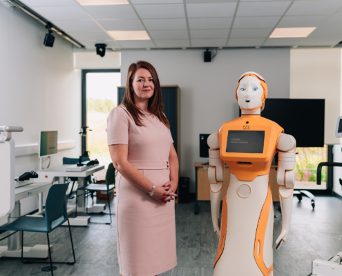 This image features a woman standing next to a humanoid robot in a modern laboratory