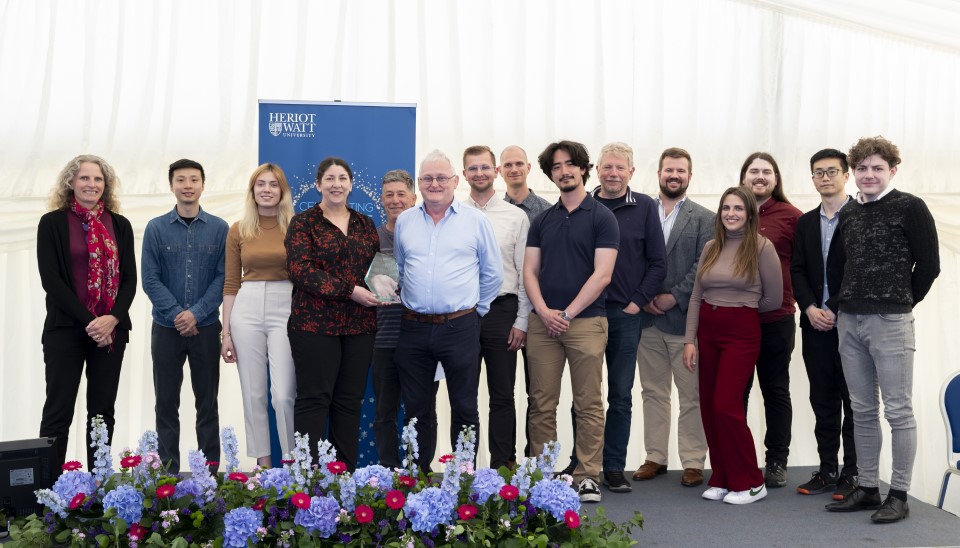 A group of people stand on stage with an award