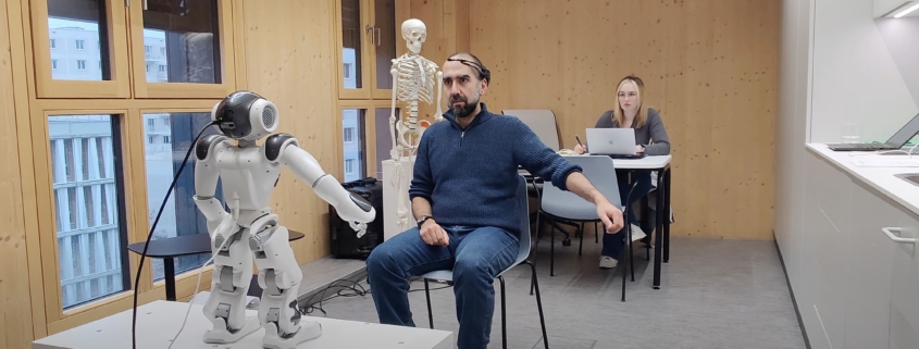 The image shows a humanoid robot interacting with a person wearing VR goggles in an indoor setting.