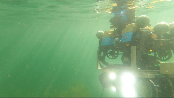 Surface vessel and autonomous underwater robot undergoing trials in Heriot-Watt University's wave tank facility