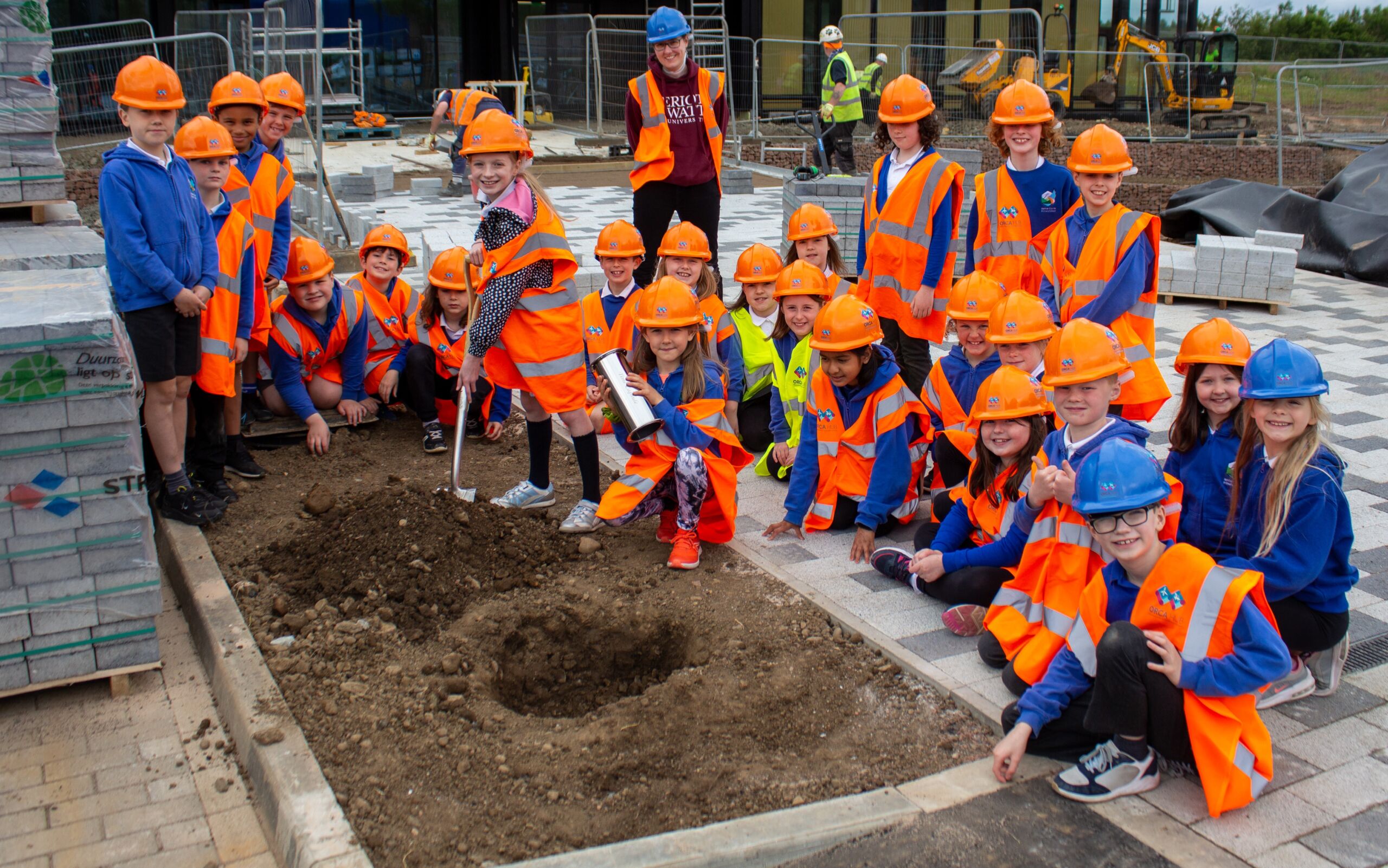 Group of primary school children pose on building site with shovel