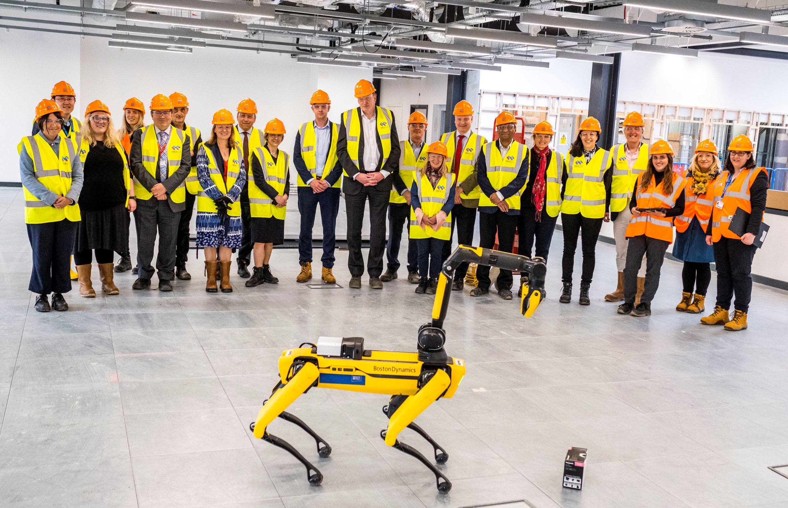 A group of people in hard hats in front of a robot dog
