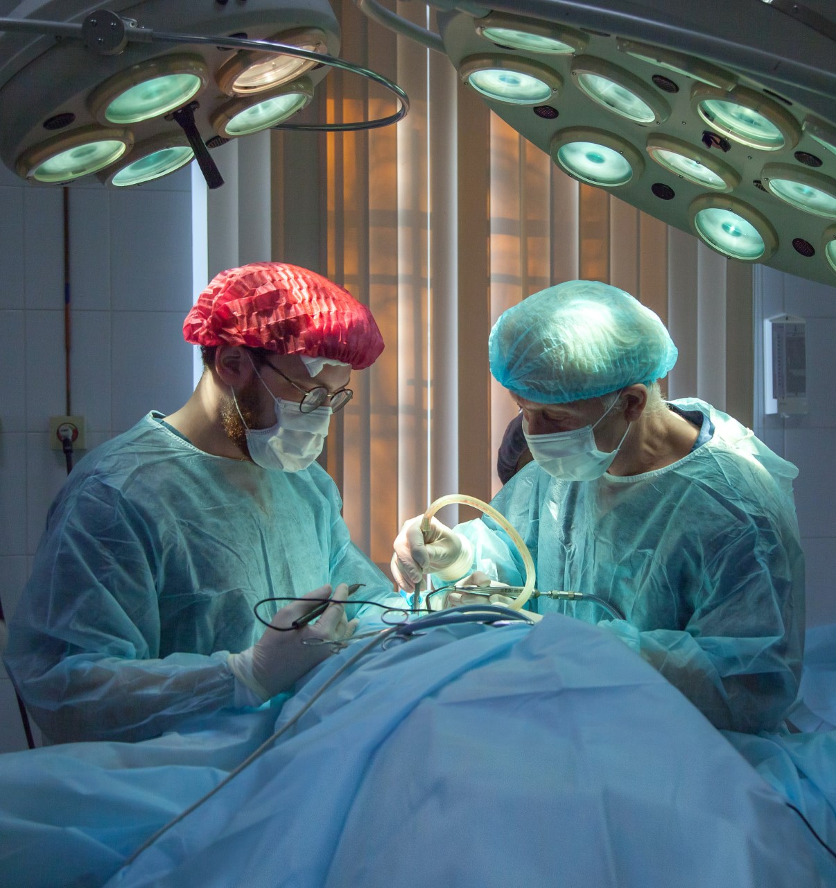 Two surgeons conduct patient surgery on hospital bed